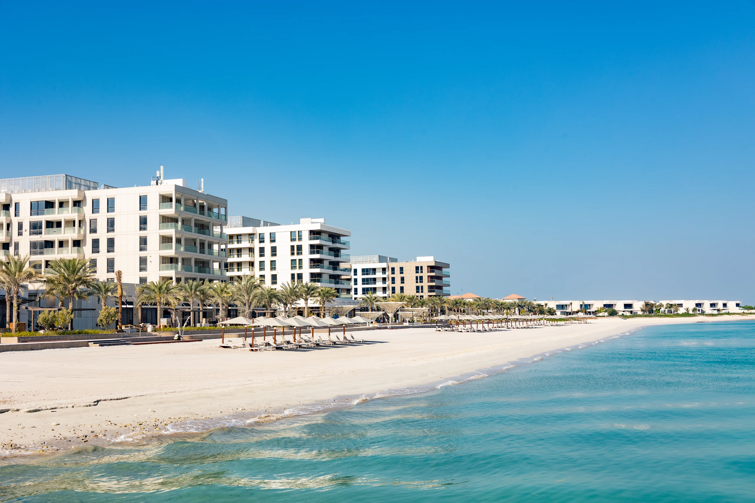 Beachfront residences, palm-lined promenade and turquoise sea at Hidd Al Saadiyat